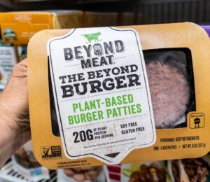 A person holds a package of Beyond Burgers in a Los Angeles supermarket aisle, to illustrate article highlighting the Beyond burger vs beef burger debate over the health impacts of plant-based vs meat products