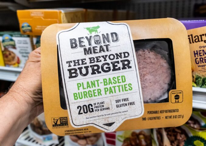 A person holds a package of Beyond Burgers in a Los Angeles supermarket aisle, to illustrate article highlighting the Beyond burger vs beef burger debate over the health impacts of plant-based vs meat products