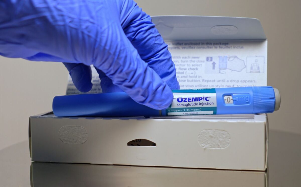 A hand in a blue glove removes an Ozempic injection pen from its box, to illustrate an article about stress eating and weight loss