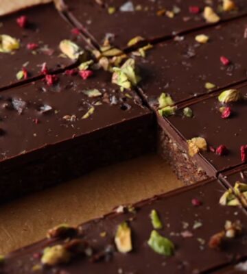 Shot of the healthy protein bars sprinkled with freeze-dried raspberries and chopped pistachios, already chilled and sliced on the baking tray