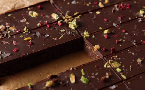 Shot of the healthy protein bars sprinkled with freeze-dried raspberries and chopped pistachios, already chilled and sliced on the baking tray