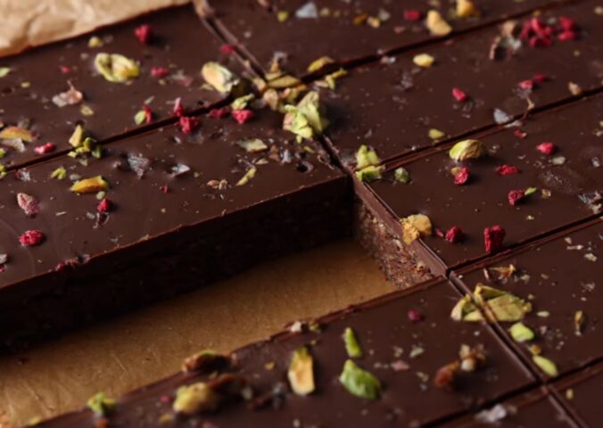 Shot of the healthy protein bars sprinkled with freeze-dried raspberries and chopped pistachios, already chilled and sliced on the baking tray