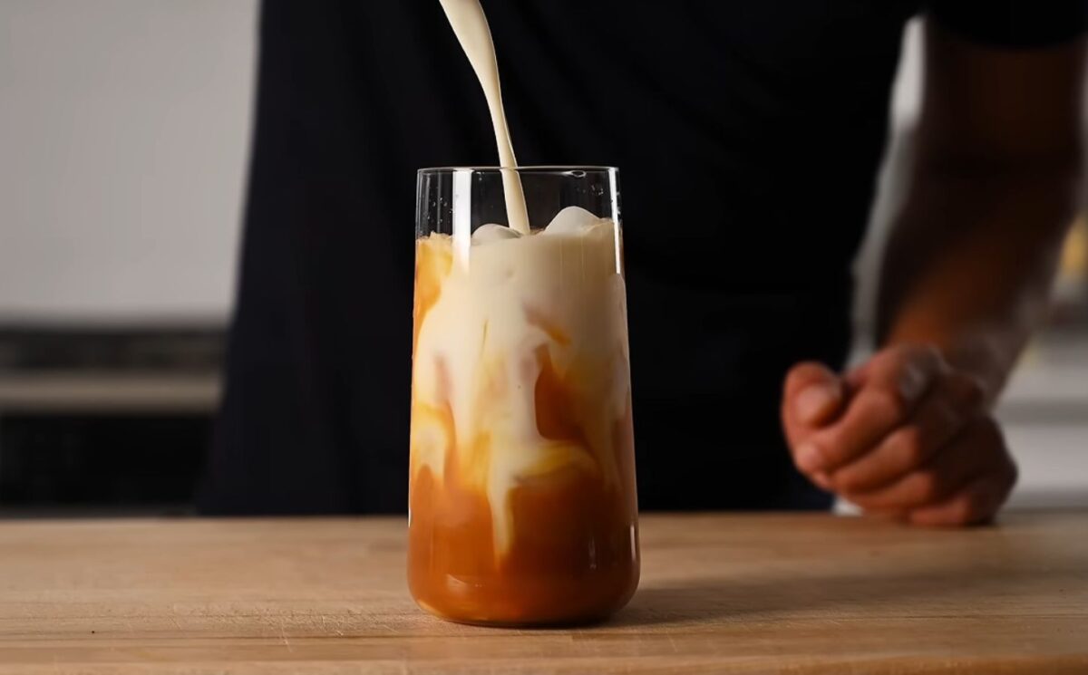 Yeung pours oat milk into the glass of vegan Thai tea