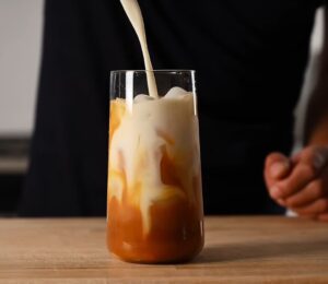 Yeung pours oat milk into the glass of vegan Thai tea
