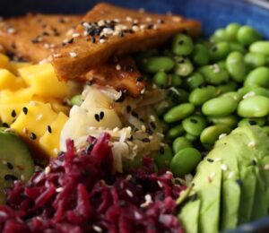 Close-up of the high-protein vegan poke bowl containing edamame, avocado, glazed tofu, and more