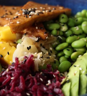 Close-up of the high-protein vegan poke bowl containing edamame, avocado, glazed tofu, and more