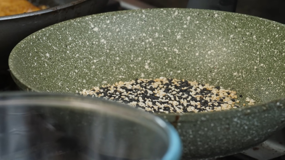Image of white and black sesame seeds toasting in a pan to make a furikake topping for the high protein vegan poke bowl