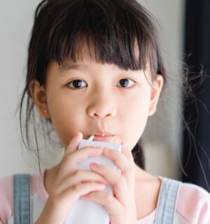 Photo shows a young school child drinking a carton of milk. California’s new state budget includes funding for school kitchens that can be used to buy dairy-free milk and plant-based foods