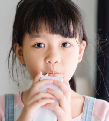Photo shows a young school child drinking a carton of milk. California’s new state budget includes funding for school kitchens that can be used to buy dairy-free milk and plant-based foods