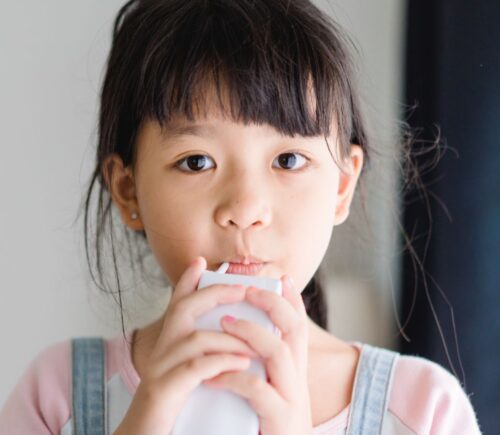 Photo shows a young school child drinking a carton of milk. California’s new state budget includes funding for school kitchens that can be used to buy dairy-free milk and plant-based foods