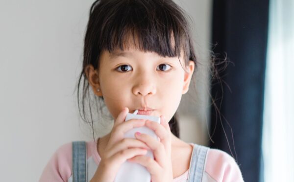 Photo shows a young school child drinking a carton of milk. California’s new state budget includes funding for school kitchens that can be used to buy dairy-free milk and plant-based foods