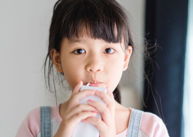 Photo shows a young school child drinking a carton of milk. California’s new state budget includes funding for school kitchens that can be used to buy dairy-free milk and plant-based foods