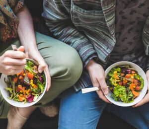 Photo shows a couple eating salad out of a bowl. Could adopting a plant-based or plant-rich diet make you more attractive? A new narrative review has found that eating less meat and more plants can change how you look, smell, and feel, and benefit your overall health.