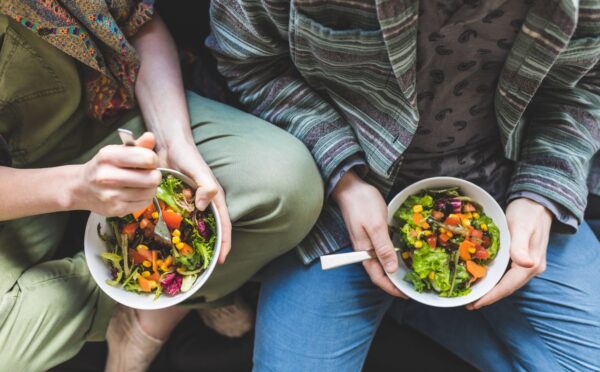 Photo shows a couple eating salad out of a bowl. Could adopting a plant-based or plant-rich diet make you more attractive? A new narrative review has found that eating less meat and more plants can change how you look, smell, and feel, and benefit your overall health.