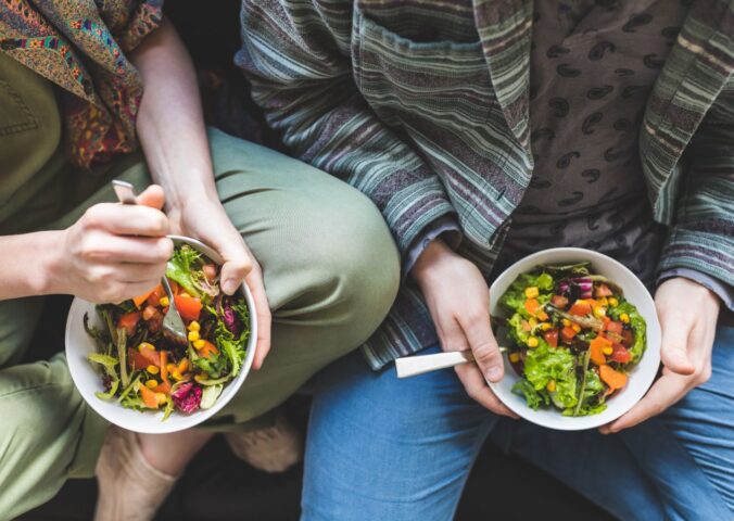 Photo shows a couple eating salad out of a bowl. Could adopting a plant-based or plant-rich diet make you more attractive? A new narrative review has found that eating less meat and more plants can change how you look, smell, and feel, and benefit your overall health.