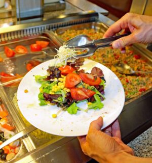 Photo shows a man putting fresh salad and vegetables on a plate in front of a buffet. The European Court of Human Rights (ECHR) has found that Switzerland violated two vegan prisoners’ “freedom of conscience” when it failed to provide them with meals consistent with their ethical beliefs