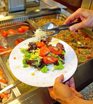 Photo shows a man putting fresh salad and vegetables on a plate in front of a buffet. The European Court of Human Rights (ECHR) has found that Switzerland violated two vegan prisoners’ “freedom of conscience” when it failed to provide them with meals consistent with their ethical beliefs