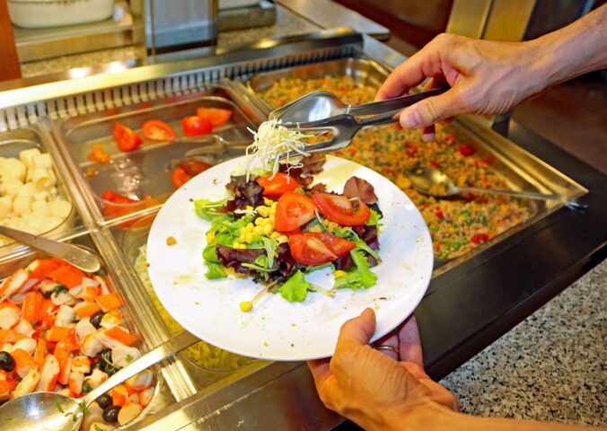 Photo shows a man putting fresh salad and vegetables on a plate in front of a buffet. The European Court of Human Rights (ECHR) has found that Switzerland violated two vegan prisoners’ “freedom of conscience” when it failed to provide them with meals consistent with their ethical beliefs