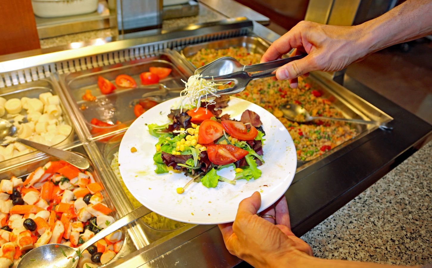 Photo shows a man putting fresh salad and vegetables on a plate in front of a buffet. The European Court of Human Rights (ECHR) has found that Switzerland violated two vegan prisoners’ “freedom of conscience” when it failed to provide them with meals consistent with their ethical beliefs