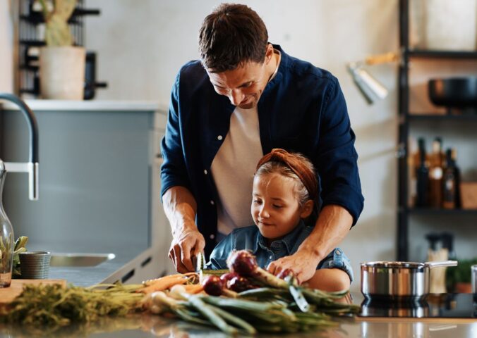 Photo shows a Dad chopping fresh vegetables with his daughter. A new study has found that children and young people around the world are not eating enough nutritious, sustainable, plant-based foods