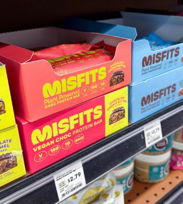 Photo shows boxes of Misfits protein bars on a shelf in the US, many of which use the phrase "plant-powered." Misfits Health has announced a new protein bar made with dairy chocolate, whey powder, and bovine collagen, and its vegan customers are not happy