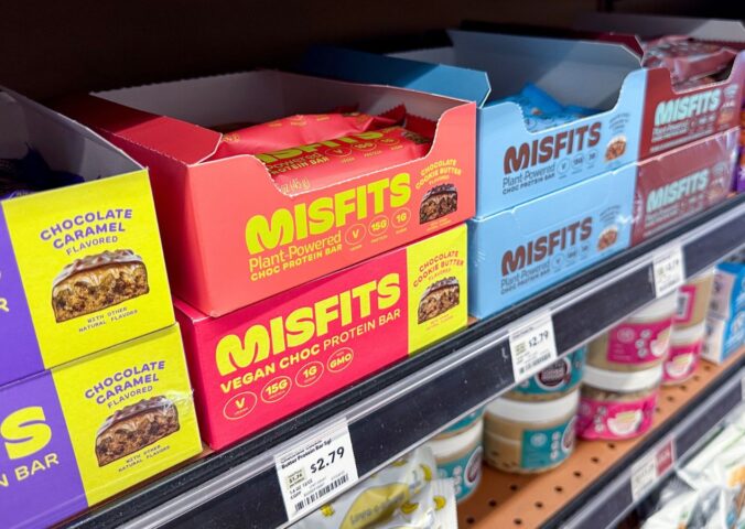 Photo shows boxes of Misfits protein bars on a shelf in the US, many of which use the phrase "plant-powered." Misfits Health has announced a new protein bar made with dairy chocolate, whey powder, and bovine collagen, and its vegan customers are not happy