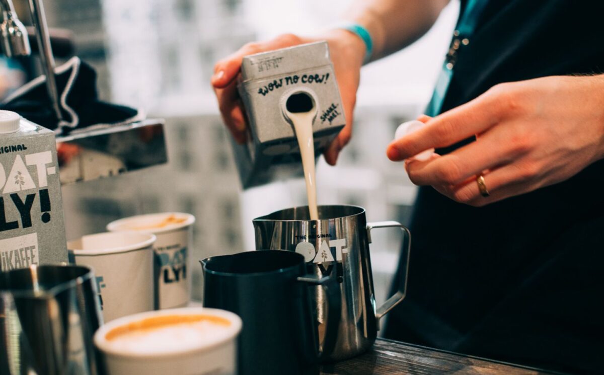 Photo shows a barista pouring Oatly Barista oat milk into a jug in a cafe. Oatly has reported profitable growth in the second quarter of 2026, primarily driven by sales of its Barista milk line