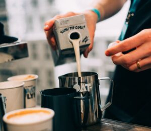 Photo shows a barista pouring Oatly Barista oat milk into a jug in a cafe. Oatly has reported profitable growth in the second quarter of 2026, primarily driven by sales of its Barista milk line