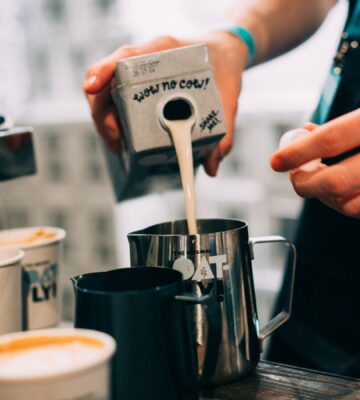 Photo shows a barista pouring Oatly Barista oat milk into a jug in a cafe. Oatly has reported profitable growth in the second quarter of 2026, primarily driven by sales of its Barista milk line
