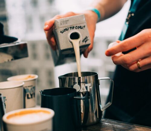 Photo shows a barista pouring Oatly Barista oat milk into a jug in a cafe. Oatly has reported profitable growth in the second quarter of 2026, primarily driven by sales of its Barista milk line