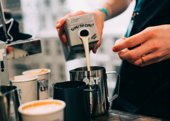 Photo shows a barista pouring Oatly Barista oat milk into a jug in a cafe. Oatly has reported profitable growth in the second quarter of 2026, primarily driven by sales of its Barista milk line