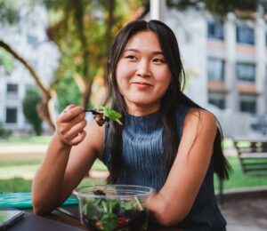 Photo shows a young woman eating lunch in front of her university building. A Peru court has ordered a major university to provide plant-based meals for its vegan student population