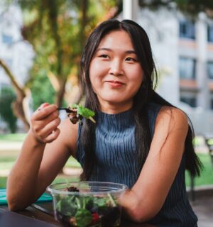 Photo shows a young woman eating lunch in front of her university building. A Peru court has ordered a major university to provide plant-based meals for its vegan student population
