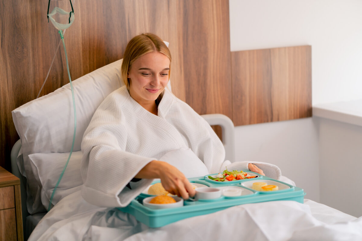 Photo shows a young woman in bed, in hospital, with a plate of mostly plant-based food. Based on his new "Make Hospital Food Healthy Again Pledge," could RFK Jr be coming round to the idea of plant-based protein?