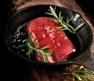Photo shows a rare steak in a cast iron pan with rosemary and salt. Cultivated protein startup MyriaMeat has made a venison breakthrough with roe deer stem cells