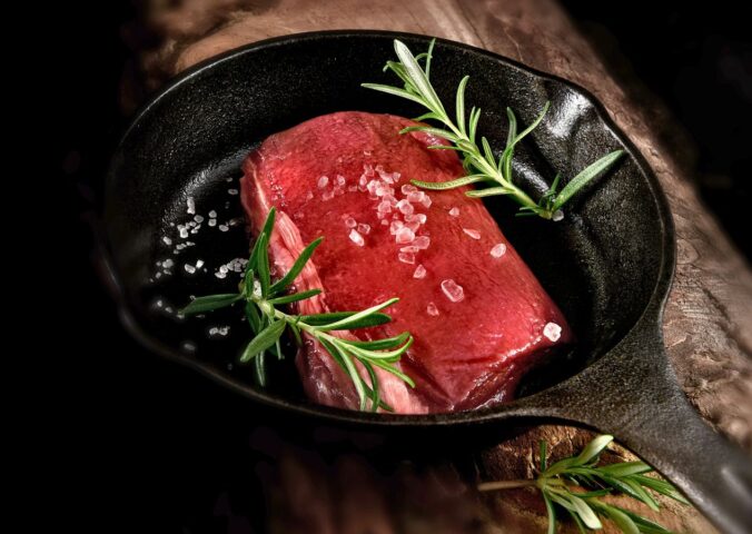 Photo shows a rare steak in a cast iron pan with rosemary and salt. Cultivated protein startup MyriaMeat has made a venison breakthrough with roe deer stem cells