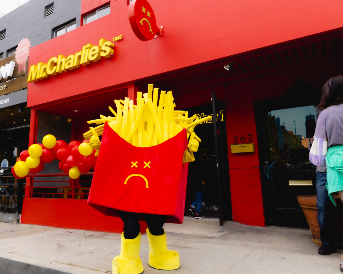 Photo shows someone in a Mr Charlie's mascot costume outside an existing branch. Vegan fast-food brand Mr Charlie’s is opening a new store this weekend and Travis Barker is expected to make a “special appearance.”
