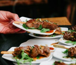 Photo shows someone placing a plate of steak down on a table alongside several other plates. The UK has published fresh guidance for companies developing new cultivated meat proteins and other novel foods