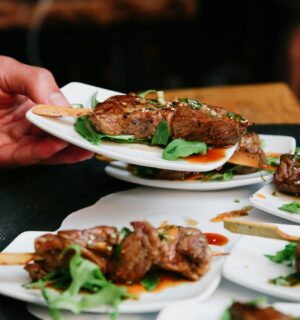 Photo shows someone placing a plate of steak down on a table alongside several other plates. The UK has published fresh guidance for companies developing new cultivated meat proteins and other novel foods