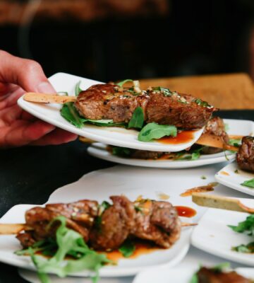 Photo shows someone placing a plate of steak down on a table alongside several other plates. The UK has published fresh guidance for companies developing new cultivated meat proteins and other novel foods