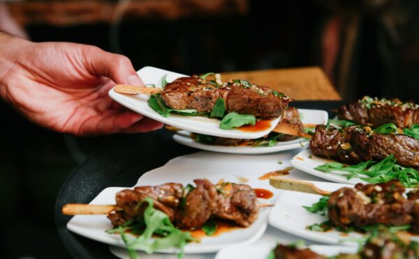 Photo shows someone placing a plate of steak down on a table alongside several other plates. The UK has published fresh guidance for companies developing new cultivated meat proteins and other novel foods