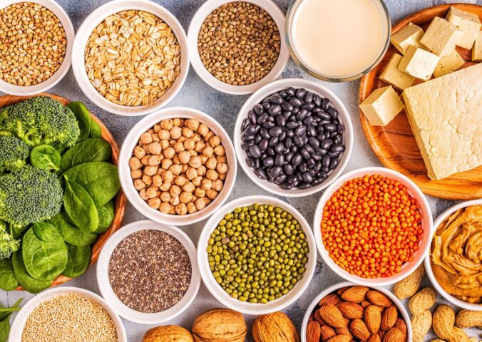Vegan protein sources including tofu, legumes, nuts, and seeds arranged together, to illustrate article on how eating less protein can boost health and longevity