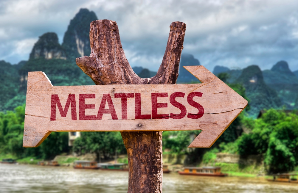 Wooden meatless sign on a forest background to illustrate article about factors that influence eating less meat.