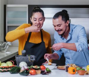 Couple eating chips and salsa surrounded by vegetables, illustrating the healthiest vegetables for men versus women