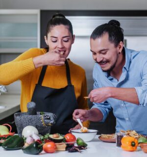 Couple eating chips and salsa surrounded by vegetables, illustrating the healthiest vegetables for men versus women