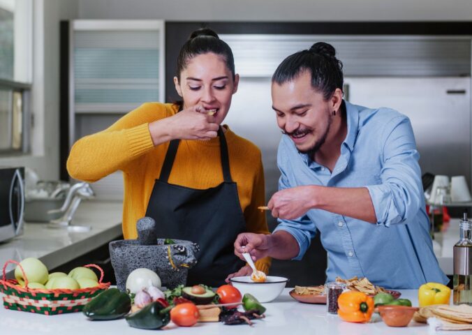 Couple eating chips and salsa surrounded by vegetables, illustrating the healthiest vegetables for men versus women