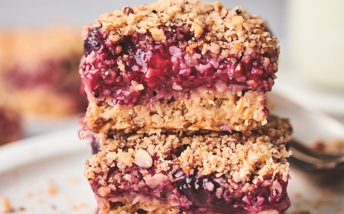 stacked breakfast berry chia bars with banana, maple syrup, rolled oats, frozen berries, and a crumble topping for late summer vegan breakfasts