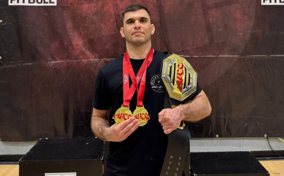 Photo shows Bernardo Ficarella, a vegan athlete and champion martial artist with black belts in both judo and Brazilian jiu-jitsu, wearing multiple medals and holding a trophy