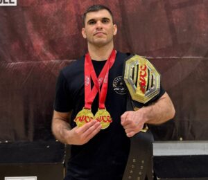 Photo shows Bernardo Ficarella, a vegan athlete and champion martial artist with black belts in both judo and Brazilian jiu-jitsu, wearing multiple medals and holding a trophy