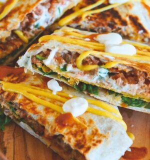 crunchy tostada wrap with corn tortilla, lentils, refired beans, vegan cheese sauce, cashew sour cream and more